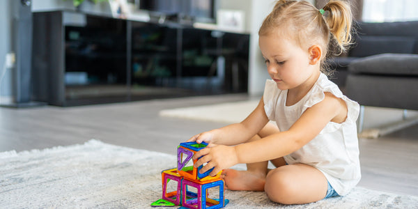 Niña rubia jugando con juguetes de construcción en la sala de una casa - imagen de nota habilidades sociales en niños